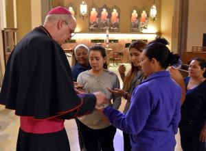 El obispo Kevin Birmingham distribuye medallas de Ntra. Sra. de Guadalupe antes de la misa.