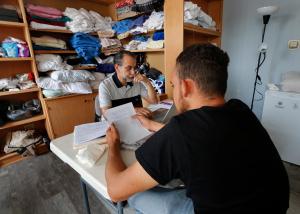 Enrique Pilarte, de Servicios Escalabrinianos para Inmigrantes y Refugiados ayuda a un migrante en busca de asilo con documentos durante el programa de duchas y desayuno en el albergue de emergencia en la iglesia Catherine of Siena-St. Lucy, el 8 de agosto.