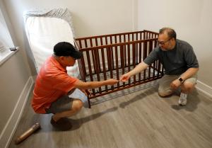 Joseph Graciosa Sr. y su hijo ensamblan una cuna en una de las habitaciones en el apartamento de Pilsen el 31 de julio.
