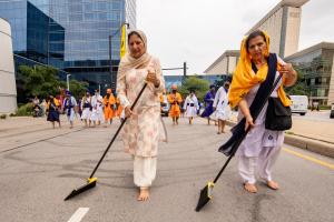 Mujeres sikh barren las impurezas de la calle en la procesión de las Religiones del Mundo el 13 de agosto.