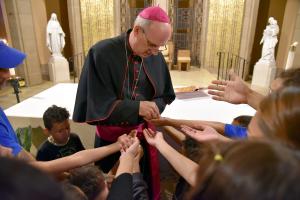 El obispo Birmingham distribuyó medallas de Nuestra Señora de Guadalupe a la mayoría de los niños y a algunos de los adultos antes de celebrar la misa para los migrantes en busca de asilo en la iglesia de St. Pascal el 18 de junio de 2023. Foto: Karie Angell Luc/Católico