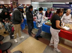 Kathy Gruszesky y Beth Beckman reparten sándwiches después de misa. La Catedral del Santo Nombre organizó una misa de Adviento para más de 500 migrantes recién llegados el 17 de diciembre, con el obispo Daniel Turley, O.S.A. Después de la misa, se les dio la bienvenida en la cafetería de la escuela Frances Xavier Warde donde recibieron alimentos, abrigos, juguetes y objetos religiosos. El ministerio de jóvenes adultos de la catedral organizó la colecta de juguetes y ropa. Foto: Karen Callaway/Católico