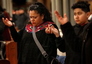 Heidy Méndez-Grimaldo y su hijo Matthew oran el Padre Nuestro durante la misa.