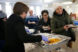 La señora Olga de León ayuda a servir comida después de misa, en la fiesta que tiene lugar en el sótano de la iglesia.
