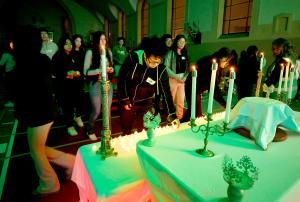 Los jóvenes depositan pequeñas velas eléctricas en el altar antes de la oración.