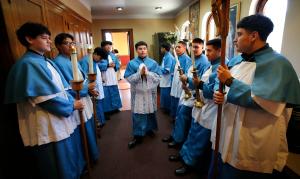Al centro, Joseph Martinez revisa que todo esté en orden con el grupo antes de que el padre Tom Boharic se les una para una oración antes de comenzar la misa el 3 de marzo en Madre de las Américas.
