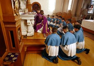 Los chicos se arrodillan mientras el padre Tom Boharic y el diácono Charles Agony ponen la Eucaristía en el tabernáculo el 3 de marzo en Madre de las Américas.