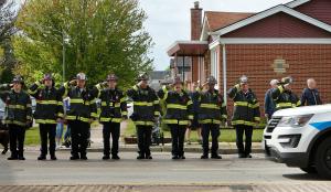 Miembros del cuerpo de bomberos de Evergreen Park saludan al paso de la procesión.