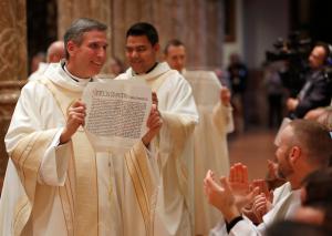 El obispo Sullivan muestra su mandato de la Santa Sede a sus hermanos sacerdotes. Foto: Karen Callaway/Católico