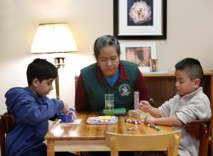 Juanita Catalán trabaja con Ayden y Ángel al principio de la clase en la que alumnos hacen actividades iniciales antes de participar en una hora de oración.