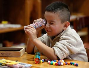 Ángel mira por un caleidoscopio durante la sesión de SPRED, el 29 de marzo en el Santuario de Des Plaines.