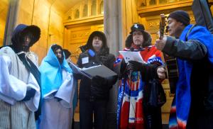 El Padre franciscano Ed Shea lidera el himno de la posada afuera de St. Peter’s en el centro de la ciudad, 110 W. Madison St., al finalizar la posada de inmigración el 15 de diciembre. Foto: Ariane Moya/Católico.