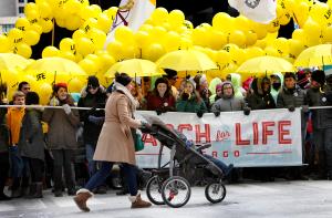 Una mujer empuja un cochecito de bebé al frente de jóvenes con una pancarta durante la Marcha por la Vida de Chicago. Foto: Karen Callaway/Católico.